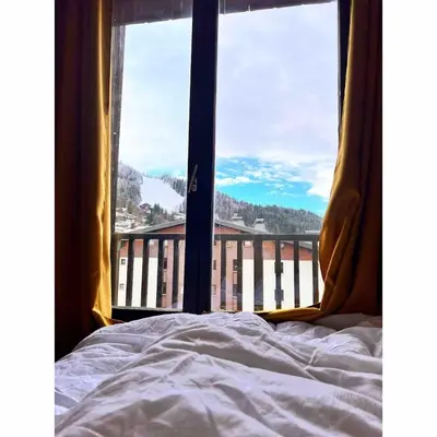 a bedroom with a bed and a view of a balcony at Joli studio hypercentre in Les Carroz d'Araches