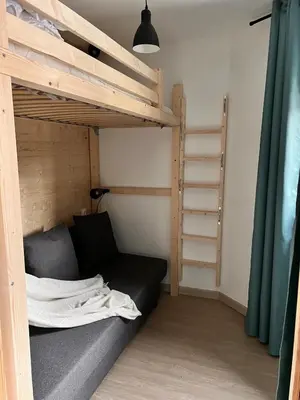 a bedroom with a bunk bed with a black couch at Joli studio hypercentre in Les Carroz d'Araches