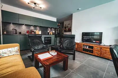 a living room with chairs and a tv and a table at Le Doran - Terrasse & Vue Mont Blanc in Sallanches