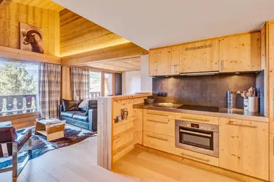 a kitchen with wooden cabinets and a living room at Appartement Bridan - Welkeys in Megève