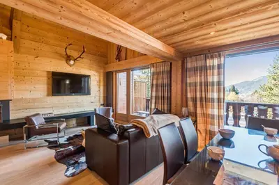 a living room with a table and chairs and a television at Appartement Bridan - Welkeys in Megève