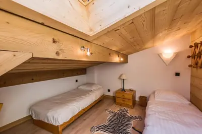 two beds in a room with wooden ceilings at Appartement Bridan - Welkeys in Megève