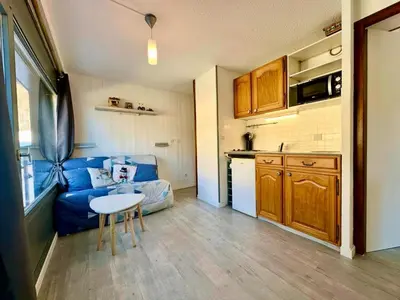 a living room with a blue couch and a kitchen at Edelweiss Résidence plein centre de la station rez de chaussée 50 m des navettes gratuites belle terrasse et grand parking privé en sous sol in Les Carroz d'Araches