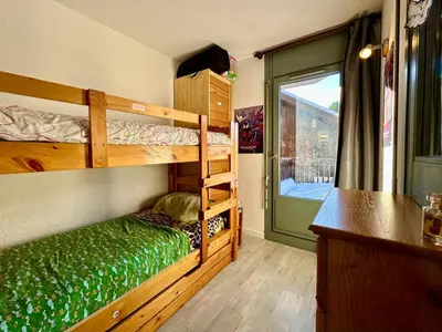 a bedroom with two bunk beds and a window at Edelweiss Résidence plein centre de la station rez de chaussée 50 m des navettes gratuites belle terrasse et grand parking privé en sous sol in Les Carroz d'Araches