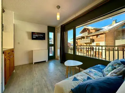 a living room with a couch and a large window at Edelweiss Résidence plein centre de la station rez de chaussée 50 m des navettes gratuites belle terrasse et grand parking privé en sous sol in Les Carroz d'Araches