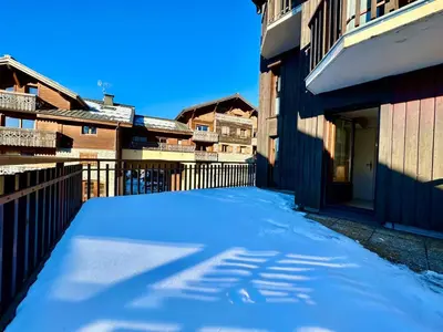 a snow covered alley with buildings and a fence at Edelweiss Résidence plein centre de la station rez de chaussée 50 m des navettes gratuites belle terrasse et grand parking privé en sous sol in Les Carroz d'Araches