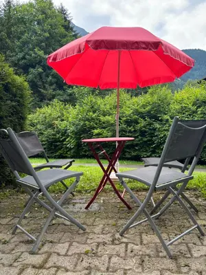 a table and two chairs with a red umbrella at Au nid du Lay in Les Contamines-Montjoie