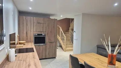 a kitchen with wooden cabinets and tables and a staircase at Le Mariloz - Vacances famille ski & montagne in Passy