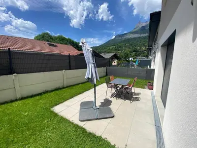 a patio with a table and chairs and an umbrella at Le Mariloz - Vacances famille ski & montagne in Passy