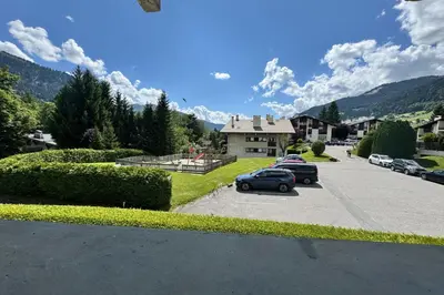a parking lot with cars parked in front of a house at Charming studio near the slopes and the city in Megève