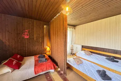 a bedroom with two beds in a wooden wall at Charming studio near the slopes and the city in Megève