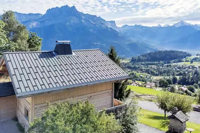 a house with a roof with mountains in the background at Chalet Mont Blanc in Cordon