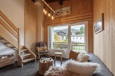 a living room with a bed and a large window at Les Chaumes - T3 moderne piscine in Sallanches