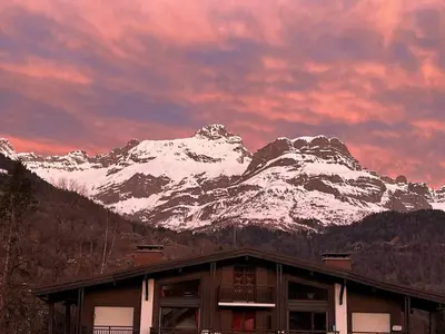a building with a snow covered mountain in the background at Les Chaumes - T3 moderne piscine in Sallanches