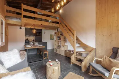 a living room with a staircase and a table at Les Chaumes - T3 moderne piscine in Sallanches