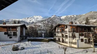a building in the snow with mountains in the background at Les Chaumes - T3 moderne piscine in Sallanches