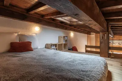 a large bed in a room with wooden ceilings at Les Chaumes - T3 moderne piscine in Sallanches