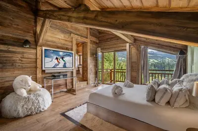 a bedroom in a log cabin with a bed and a television at Megeve Luxury Estate The Royal Alpine Retreat with Mont Blanc View - Chalet Maille in Demi-Quartier