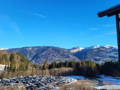 a parking lot with parked cars and mountains in the background at Jardins Alpins A N 20 - 2P6 in Morillon