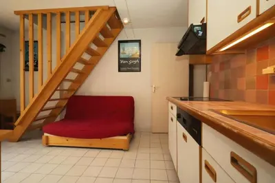 a red chair in a kitchen with a staircase at Résidence Les Chamois - Les Chamois MAE-0143 in Les Houches