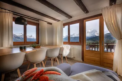 a living room with a table and chairs and windows at Appartement 10 personnes au pied des pistes vue Mont Blanc in Combloux