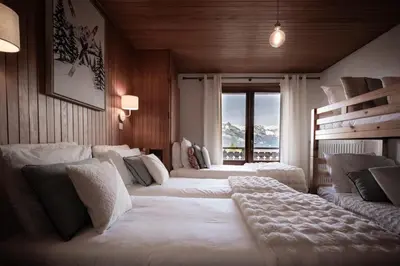 a bedroom with three beds and a large window at Appartement 10 personnes au pied des pistes vue Mont Blanc in Combloux