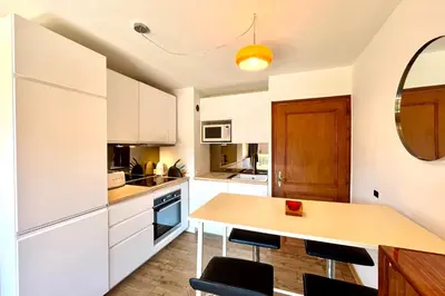 a kitchen with white cabinets and a wooden table at Le 2ème Ciel in Megève