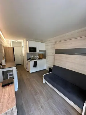 a living room with a black couch and a kitchen at L'appart 313 - La Forclaz in Chamonix-Mont-Blanc