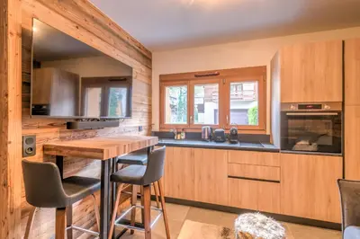 a kitchen with wooden cabinets and a wooden table at Studio Berrier - Welkeys in Megève