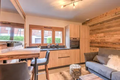 a kitchen and living room with a couch and a table at Studio Berrier - Welkeys in Megève