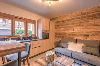 a living room with a couch and a kitchen at Studio Berrier - Welkeys in Megève