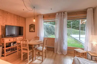 a living room with a dining room table and a television at Appartement Vinson - Welkeys in Megève