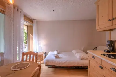 a room with a bed and a table and a kitchen at Appartement Vinson - Welkeys in Megève