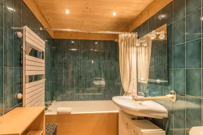 a bathroom with green tiled walls and a sink and a tub at Appartement Vinson - Welkeys in Megève