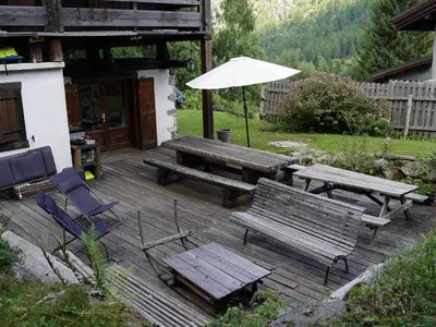 a patio with a table and benches and an umbrella at Nos Maisons Cosy - Vallorcine in Vallorcine