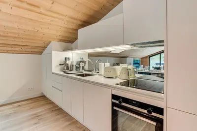 a kitchen with white cabinets and a wooden ceiling at Apartment Castorettes, Alpes Trave, Sleeps 6 to 7 in Chamonix-Mont-Blanc