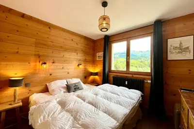 a bedroom with a bed with a wooden wall at Refuge de la Fontaine in Megève