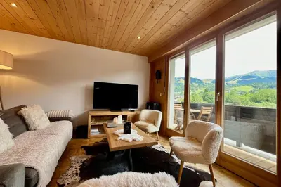a living room with a couch and chairs and a tv at Refuge de la Fontaine in Megève