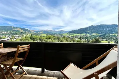 a balcony with a table and chairs and mountains at Refuge de la Fontaine in Megève