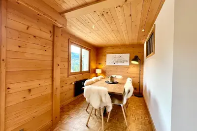 a dining room with wooden paneling and a table with chairs at Refuge de la Fontaine in Megève