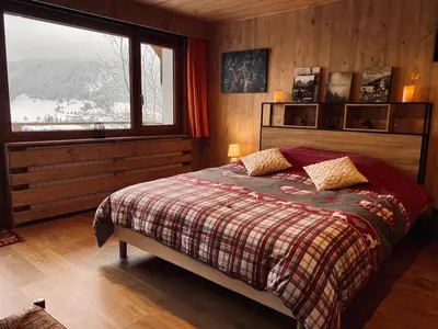 a bedroom with a bed and a large window at Gîte de l Auguille in Megève