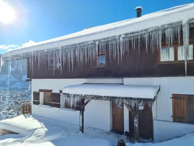 a house covered in icicles with snow on it at Gîte de l Auguille in Megève