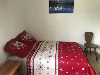 a bedroom with a bed with a red and white blanket at Samoëns studio 4 personnes idéalement situé in Samoëns