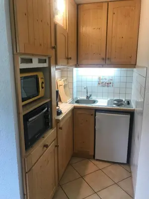 a small kitchen with a microwave and a sink at Samoëns studio 4 personnes idéalement situé in Samoëns