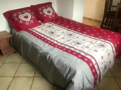 a bed with red and white sheets and red pillows at Samoëns studio 4 personnes idéalement situé in Samoëns