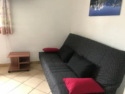 a couch with red pillows in a room at Samoëns studio 4 personnes idéalement situé in Samoëns