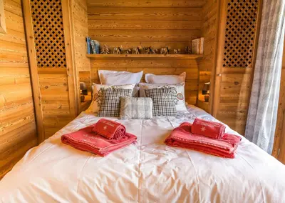 a bed with two red pillows on top of it at Modern Chalet Near Megève With Somptuous Views in Combloux