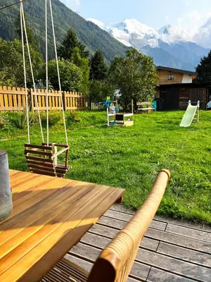 a wooden porch swing in a yard with mountains at Le point de vue in Chamonix-Mont-Blanc