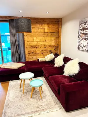 a living room with a red couch and two tables at Le point de vue in Chamonix-Mont-Blanc