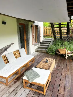 a patio with two couches and chairs on a wooden deck at Le point de vue in Chamonix-Mont-Blanc